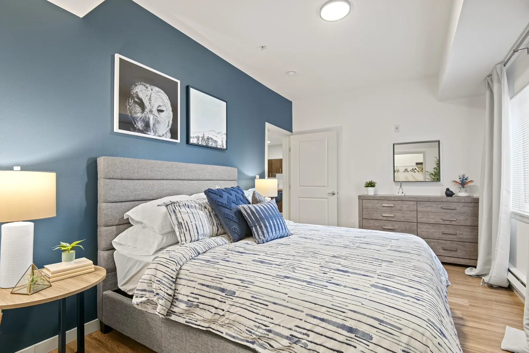 Bedroom with large windows and blue accent wall at VUE25 apartments for rent in Tacoma