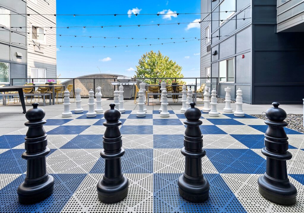 a courtyard with a Chess board and pieces in the middle
